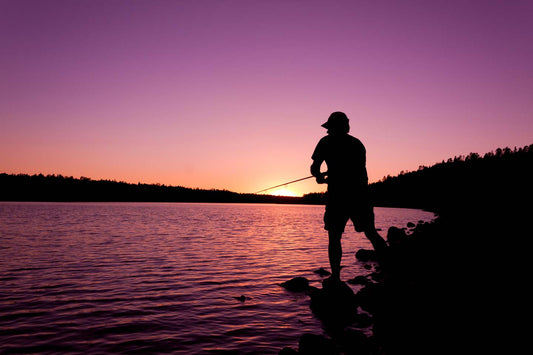 A fisherman silhouetted by the sunset on a lake in Minnesota