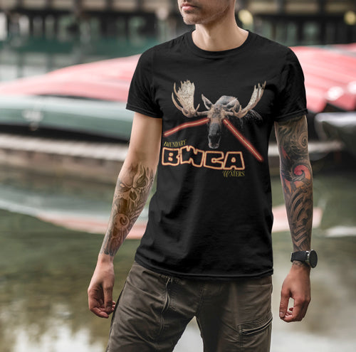Man wearing a Boundary Waters shirt while standing in front of red canoes on a northern lake