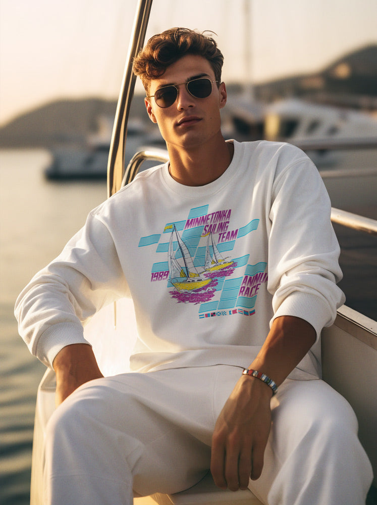 Man wearing a Minnetonka Sailing Team sweatshirt while sitting on a sailboat on Lake Minnetonka.