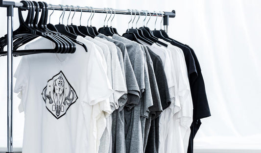 a row of several white, gray and black graphic tees hanging on a rolling clothes rack